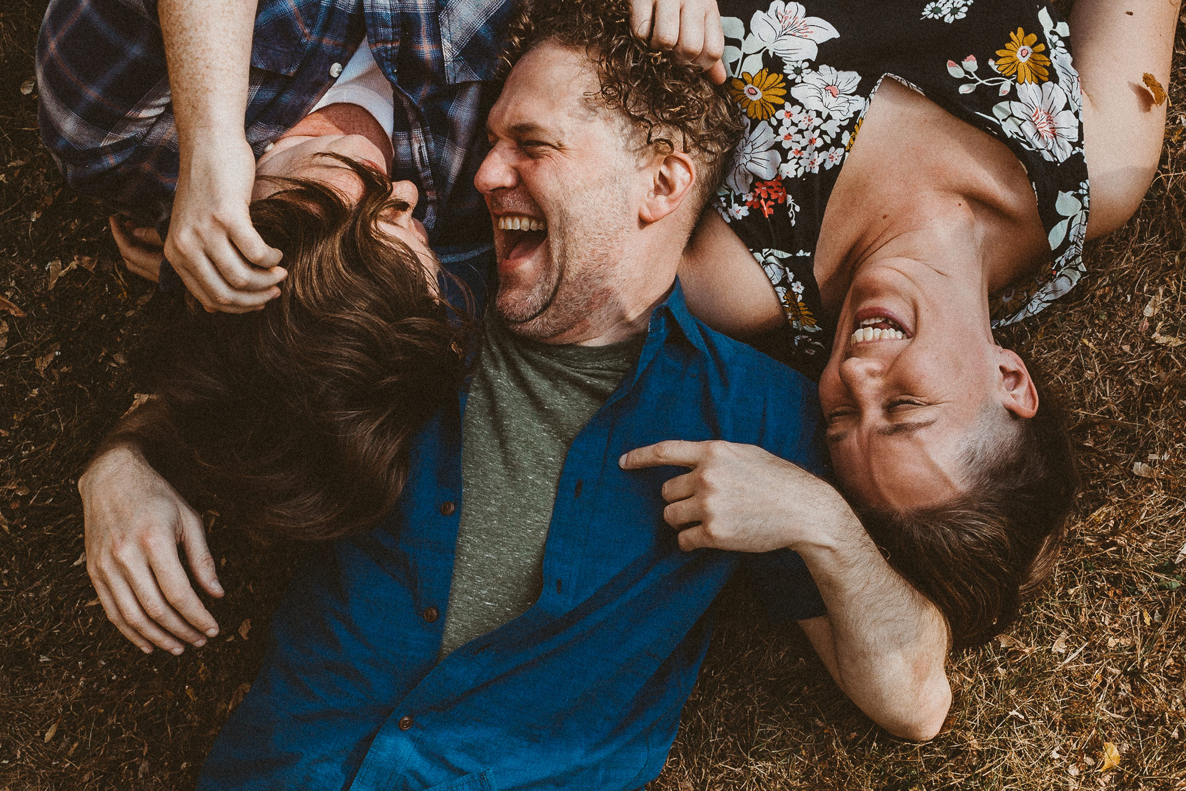 family lays down in the grass in their colorado yard, smiling and laughing