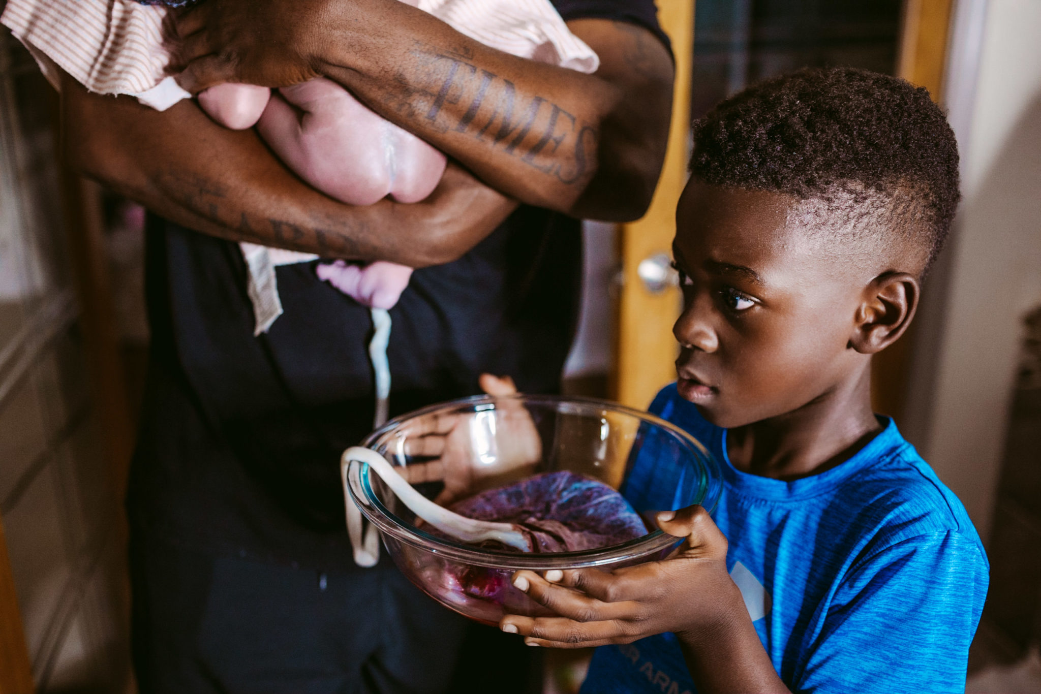 black homebirth - boy holds placenta with cord attached to baby