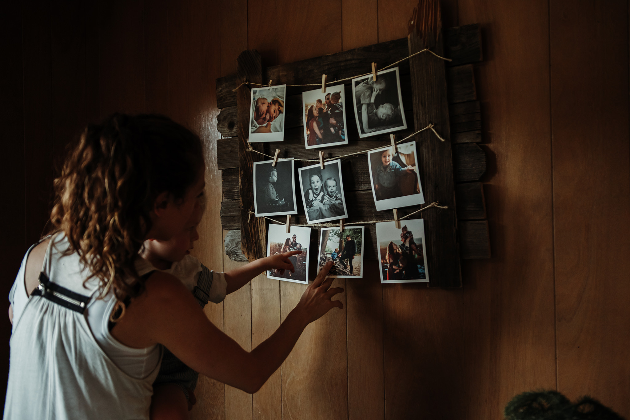 mother and child looking at Polaroid portraits on the wall in their home