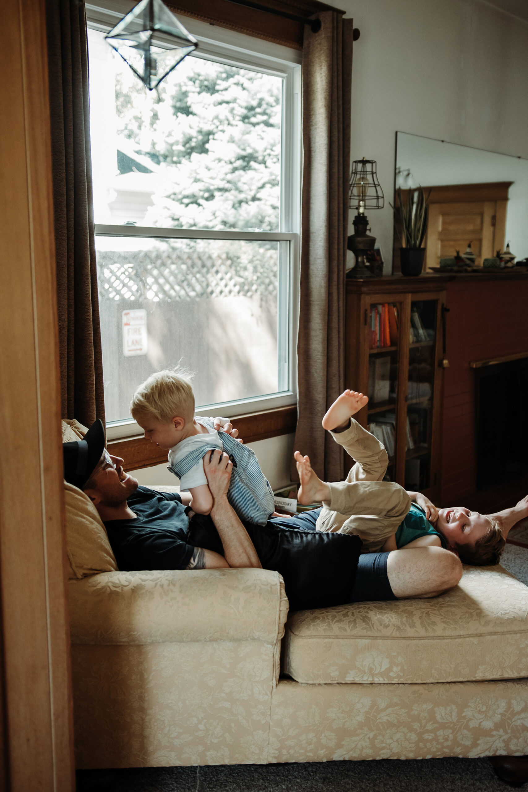 father playing with children on couch in living room