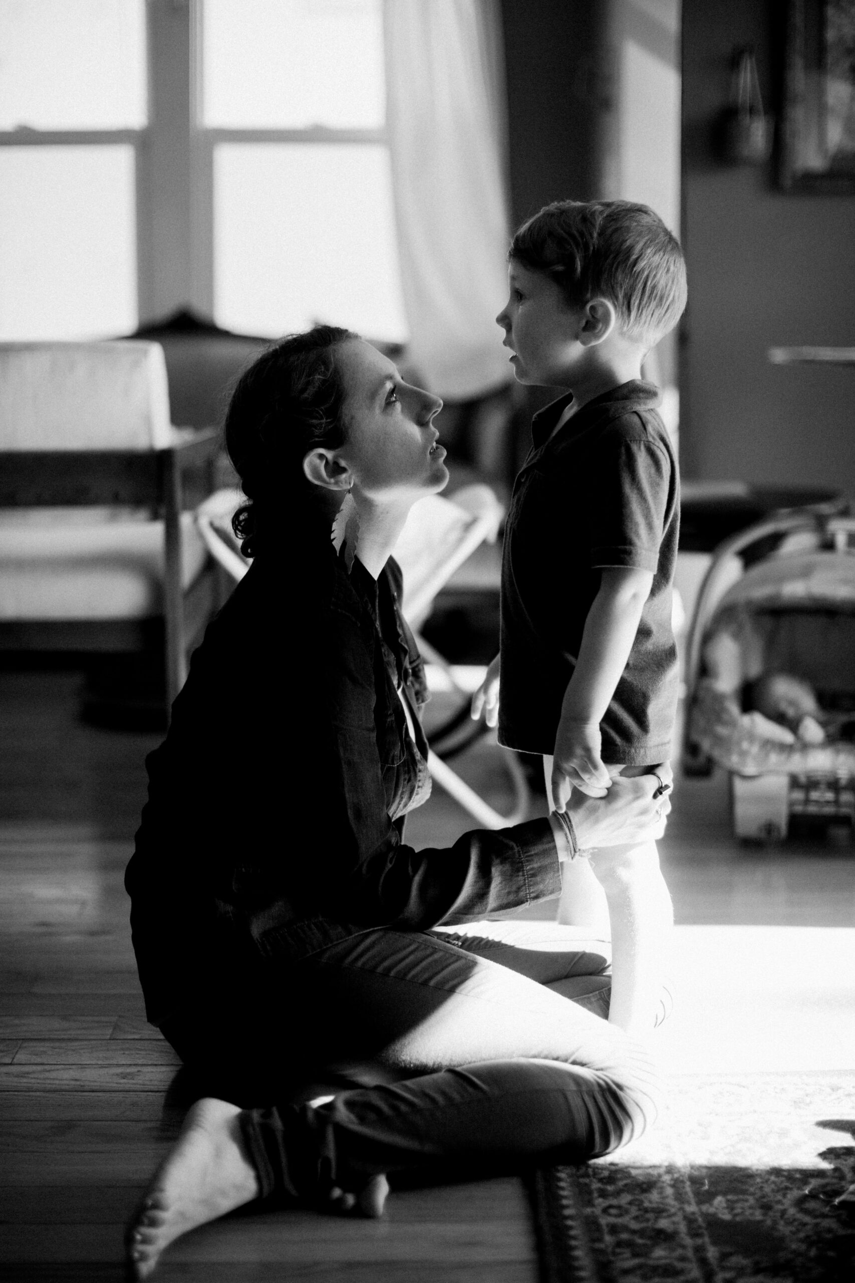 mother soothing crying child in black and white in their home