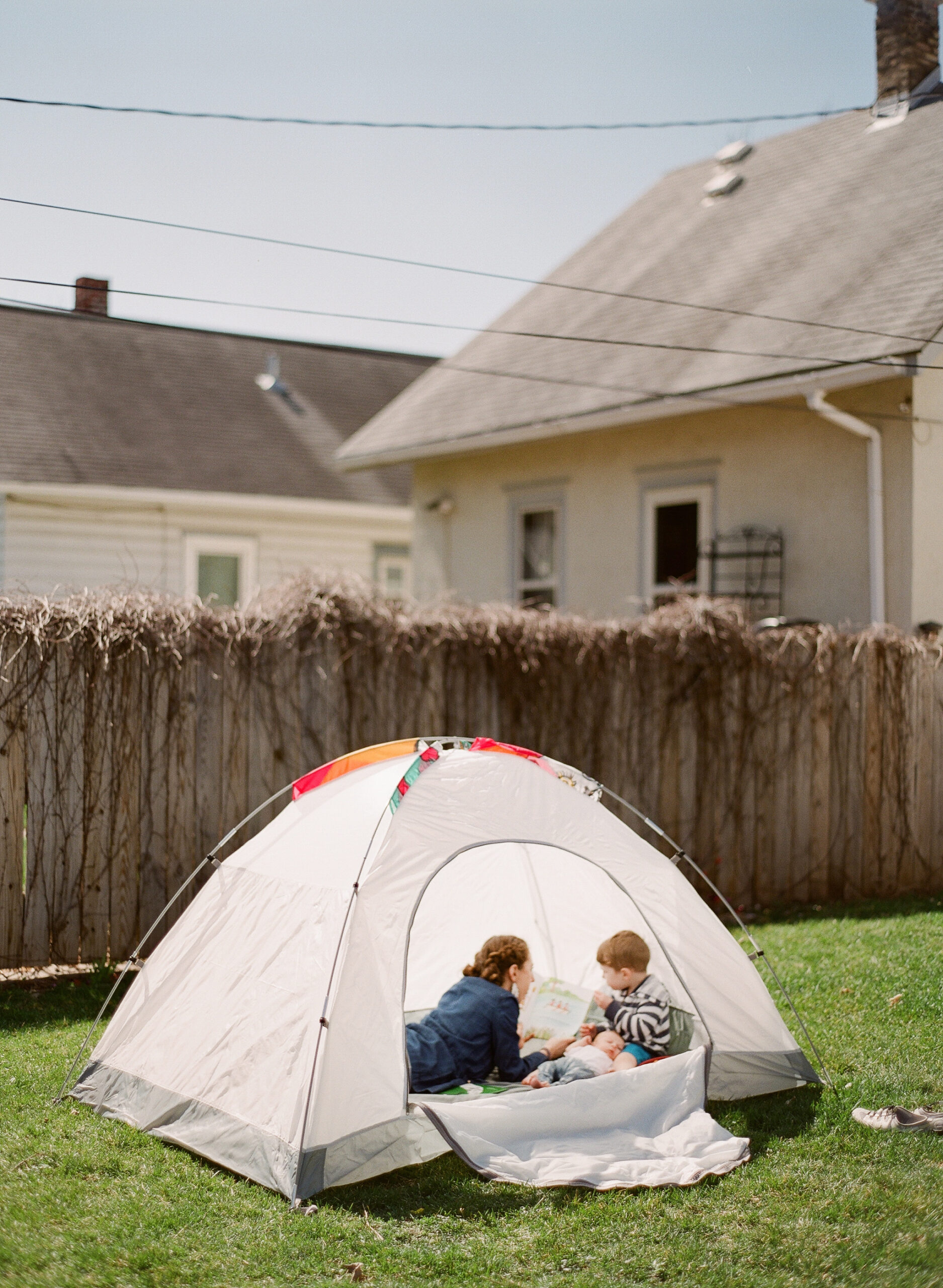 mama and children read books in tent in backyard