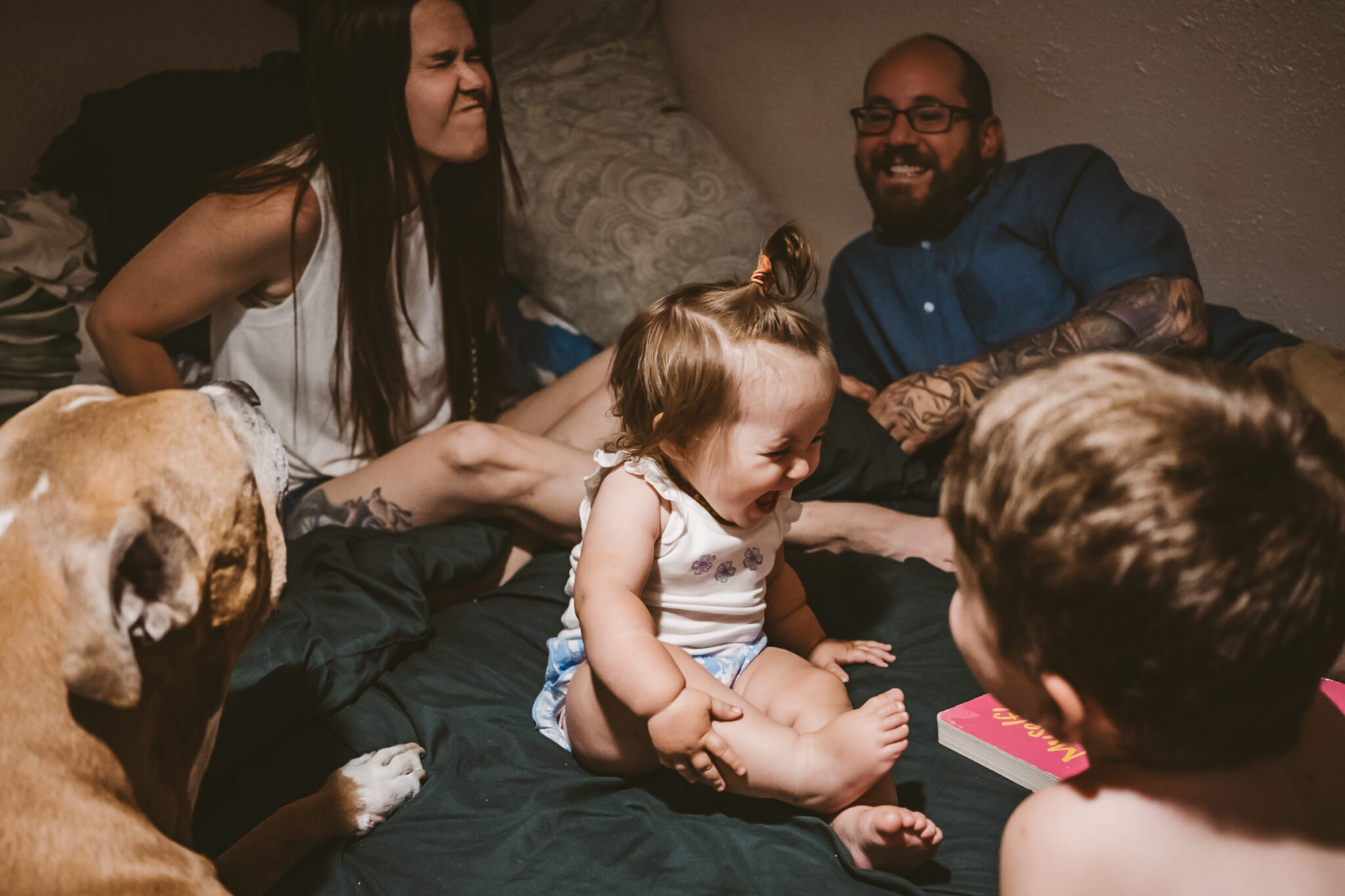 family all giggling and laughing on bed in their home